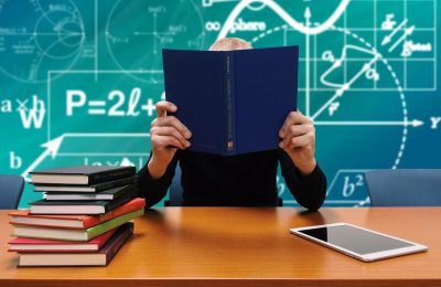 学生在宿舍书桌前用手机处理证件照，桌上放着考试报名资料